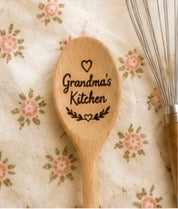Engraved wooden spoon with Grandma's Kitchen text and heart on a floral fabric background