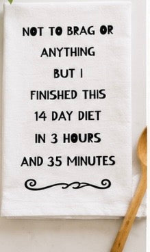 White kitchen towel with humorous diet joke text and decorative flourish with wooden spoon